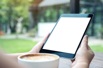 Mockup image of a woman holding black tablet pc with white blank screen with coffee cup on table and nature background