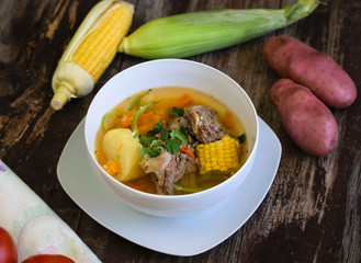 Traditional Chilean Cazuela de Vacuno or Carne beef soup with potato, corn, pumpkin, carrot, bell pepper, onion and rice, coriande. Decorated with tomatos, potatoes and fresh corn. 