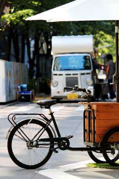 A Scenery Of A Holiday In The Business Area Of Tokyo Where A Bicycle With Umbrella And Food Truck Line Up On The Road