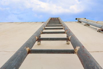 Stair old vertical industrial metal rusted to Water tank no safety rails on blue sky background...