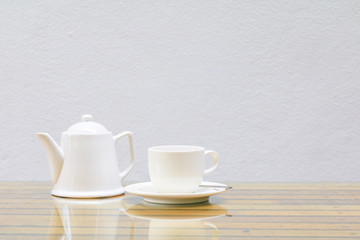 coffee cup and teapot white On the glass table wooden and a cement wall background. copy space