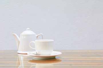coffee cup and teapot white On the glass table wooden and a cement wall background. copy space