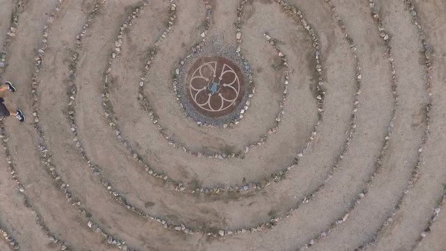Ascending aerial of a woman walking a labyrinth