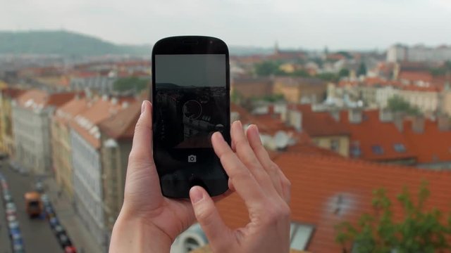 young woman is taking photos of Prague panorama, close-up view of hands