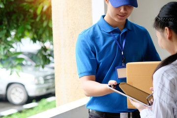 Woman appending signature sign on tablet after accepting receive boxes from delivery man, woman sign on digital tablet, receive delivery concept