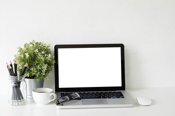 Workspace laptop computer, coffee cup and plant decorate on white office desk.