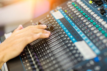 Blur Photo Hand adjusting audio mixer. sound engineer hands working on sound mixer in live concert. DJ controlled the sound system by mixer equalizer in concert or wedding hall.