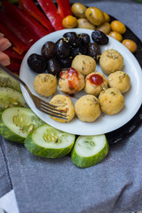 Woman hands take, hold duddha bowl with chickpea falafel balls, tomato sauce, olives, cucumbers, red pepper. Vegan vegetables lunch, vegetarian dinner, healthy dietary food