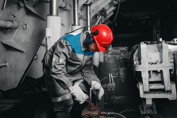 Young miner man underground in mine for coal mining overalls is busy with work, repairing against backdrop of equipment. Portrait.