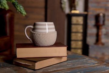 Close up big white cup on books , vintage filter.Hot coffee or tea, cocoa, chocolate cup on book with copy space,against the background of a bookshelf. Pile of books, cup on a table in the library