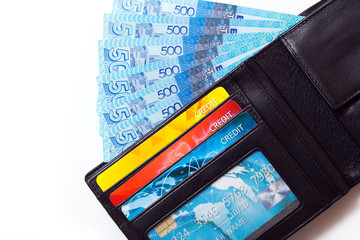 Closeup of a black leather wallet with colourful credit cards and kazakhstani tenge banknotes in it, isolated on white background