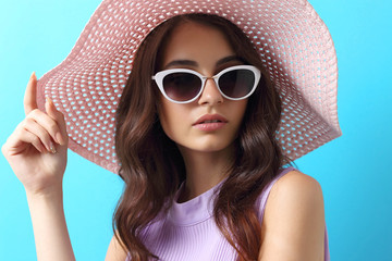 Fashion portrait of young woman wearing hat and sunglasses.