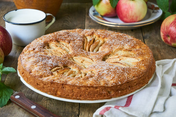 Homemade pie with apple slices on a wooden background