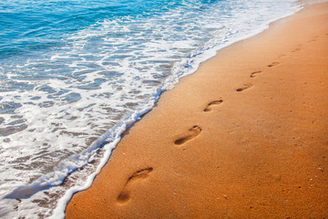 beach, wave and footprints at sunset time