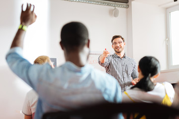 Yes you. Cheerful friendly speaker conducting a business workshop and pointing to a student raising...