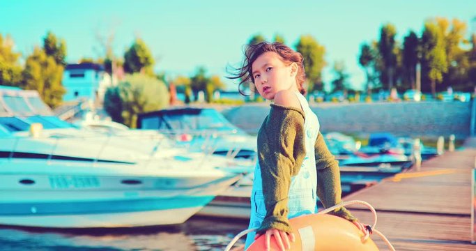 Girl with a life buoy on a yacht pier