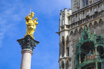 München Marienplatz Mariensäule Statue Detail vor blauem Himmel mit neuem Rathaus auf der rechten...