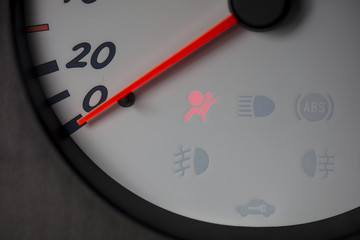 A car's white dashboard with a red airbag light.