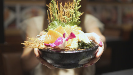 Beautiful asian woman offer salmon shasimi in japanese restaurant