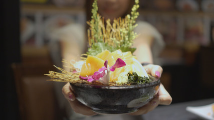 Beautiful asian woman offer salmon shasimi in japanese restaurant