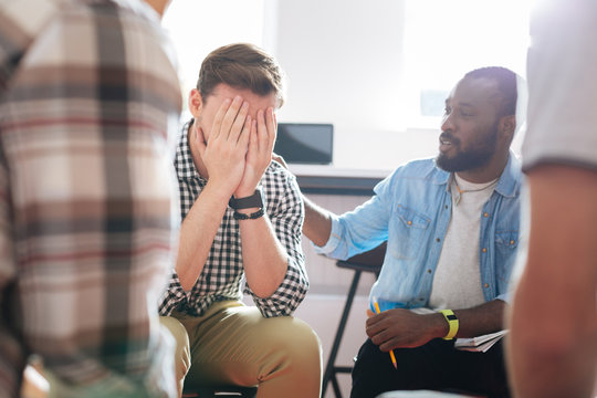 Hiding Face. Kind Reliable Man Supporting His Crying Friend And Putting Hand On His Shoulder