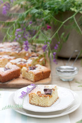 Pieces of fruit pie with pieces of plums and peach and a bouquet of flowers on a wooden table. Rustic style.