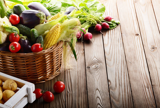 Basket of Organic vegetable food ingredients and crate of potatoes on wood background