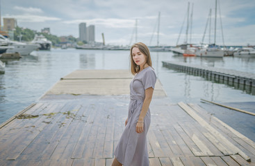 Woman in dress enjoys a walking near by the pier.