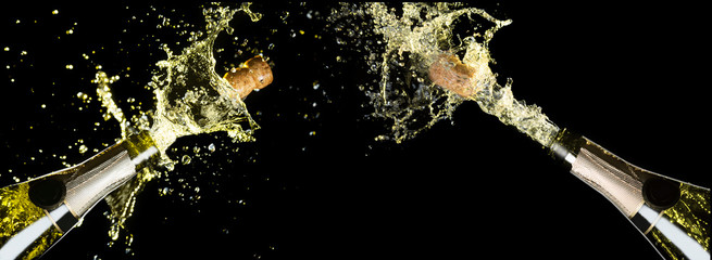 Celebration theme with explosion of splashing champagne sparkling wine bottles on black background © Nikolay N. Antonov