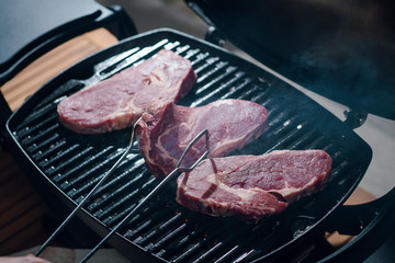Close up shot of man cooking beef steak on a grill. Raw steak. BBQ
