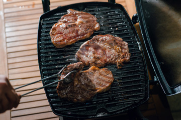 Top view of man cooking dinner. Well done steaks on the grill.
