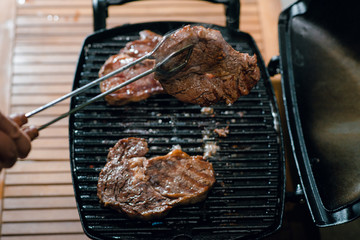 Top view of man cooking dinner. Well done steaks on the grill. BBQ evening on the backyard