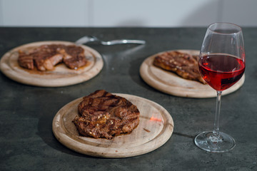 Well done steaks on the wooden plates on the table. Romantic evening with steaks and red wine.