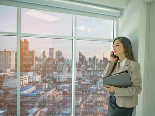 Fototapeta premium Modern business women use mobilephone talk about stock market white looking out of the window