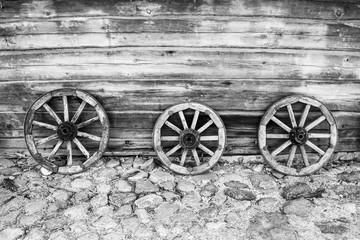Fototapeta na wymiar Old Wooden Wheels for Horse Cart on the Wooden Wall of the Stables.
