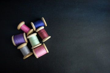 Set of pastel colors thread for sewing on a black background. Set of threads on bobbins retro...