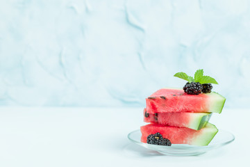 Watermelon sliced pie with blackberries and mint leaf on blue pastel background with copy space.