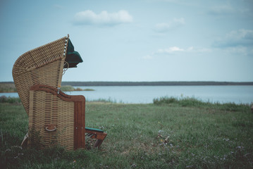 Beach chair on a meadow by the water, at the lake. Atmospheric in the evening light in a moody mood