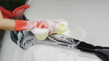 hands holding sponge to washing car