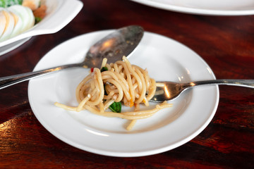 fork for eating spaghetti spicy bacon & ham on white dish set on table