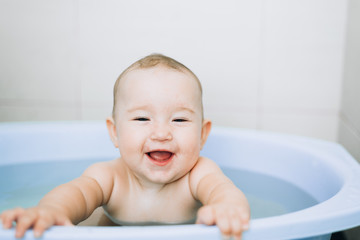 little girl baby is bathed in the blue basin in the bathroom is very fun