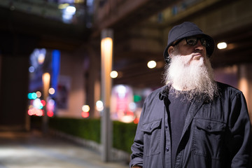 Mature bearded tourist man waiting in the city streets at night