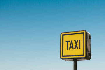 Modern taxi sign against the blue sky.