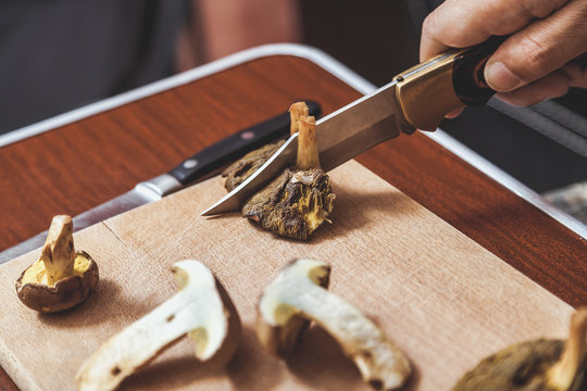 Hands cut raw mushrooms with sharp knife