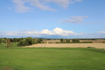 Fototapeta na wymiar Golf green overlooking farmers field