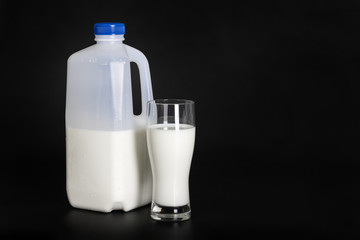 A bottle of milk and glass on a dark background.