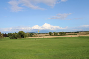 Fototapeta na wymiar Golf green overlooking farmers field