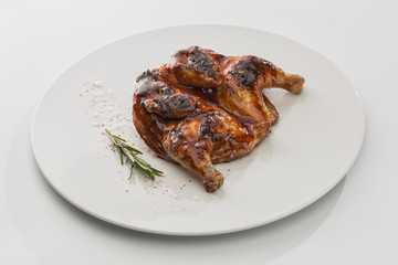 baked chicken with salt and rosemary on a plate isolated on white background