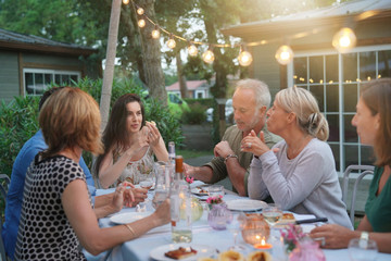 Friends enjoying summer barbecue dinner in garden