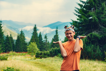 Funny guy teenager stands on the mountain meadow